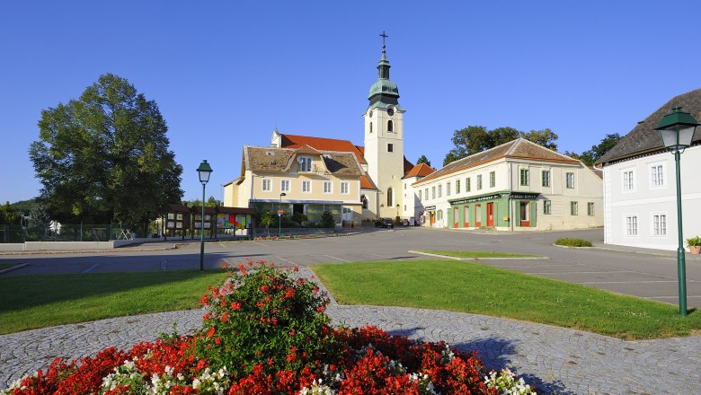 Hauptplatz in Sitzendorf mit Kirche und Blumenbeet.