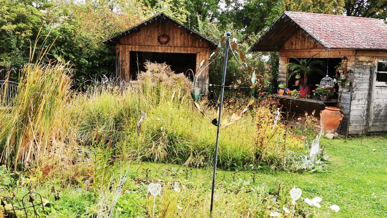 Ein Garten mit zwei Holzhütten, umgeben von Pflanzen und Dekorationen.