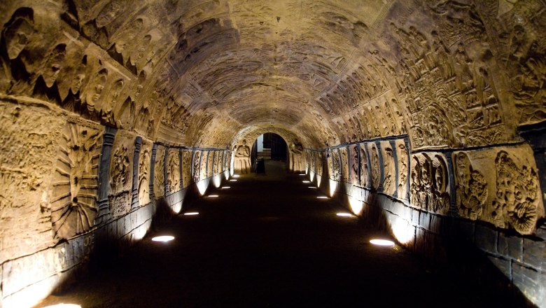 Ein beleuchteter, gew&ouml;lbter Tunnel mit kunstvollen Reliefs an den W&auml;nden.