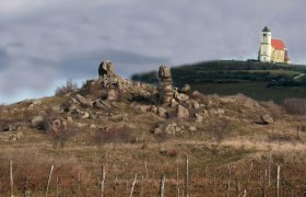 Landschaft mit Felsenformationen und Kirche im Hintergrund.