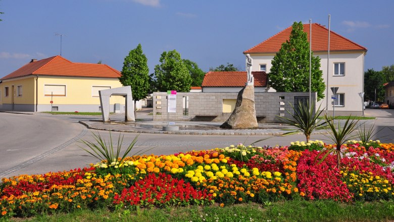 Blumenbeet und Skulptur auf dem Hauptplatz von Mailberg.