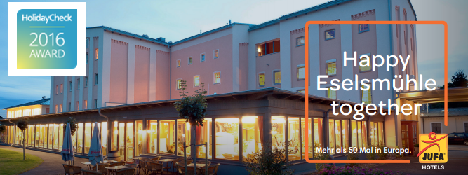 Außenansicht des JUFA Hotels bei Abenddämmerung mit HolidayCheck Award 2016 Logo.