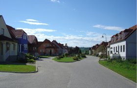 Straße in Alberndorf mit bunten Häusern und blauen Himmel.