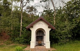 Kleine Kapelle im Wald mit der Aufschrift 'St. Hubertus'.