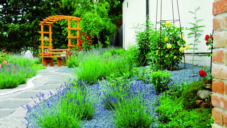 Ein gepflegter Garten mit Lavendel, einem Holzpavillon und gepflasterten Wegen.