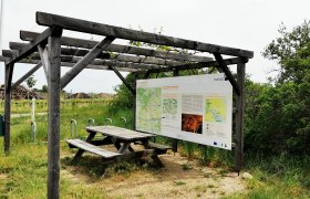 Radlerrastplatz mit Holztisch und Infotafel an der Weinstraße im Weinviertel.