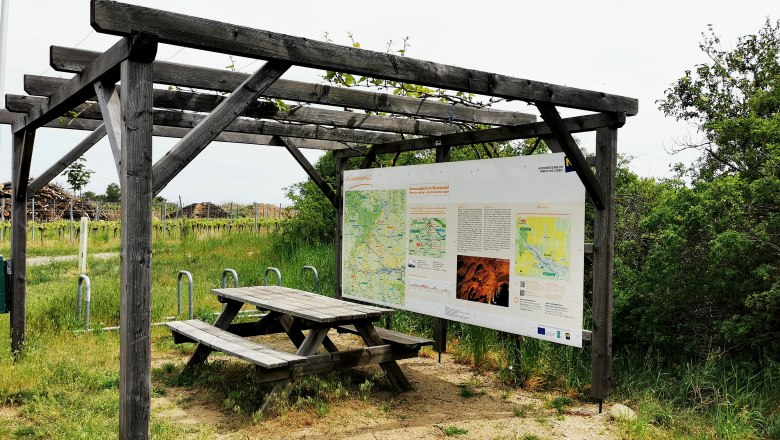 Radlerrastplatz mit Holztisch und Infotafel an der Weinstraße im Weinviertel.