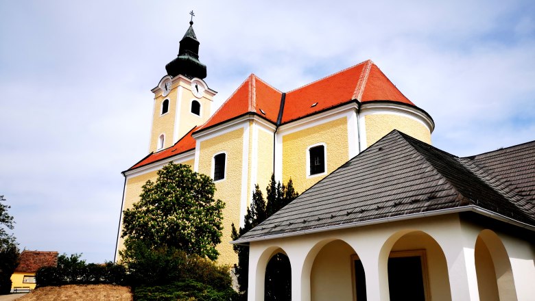 Pfarrkirche St. Nikolaus in Röschitz mit gelber Fassade und rotem Dach.