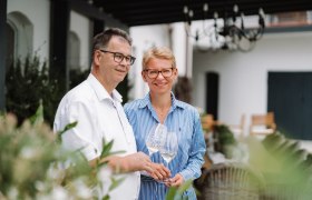 Zwei Personen stehen drau&szlig;en und halten Weingl&auml;ser.
