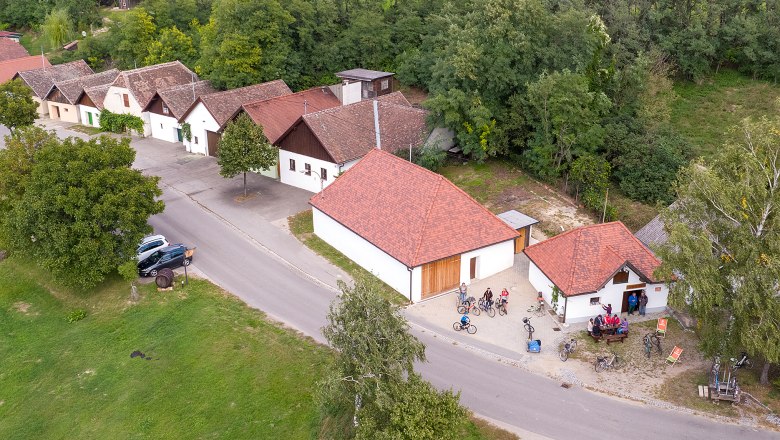 Luftaufnahme von Jetzelsdorf mit traditionellen Gebäuden und Menschen auf Fahrrädern.