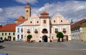 Historisches Gebäude in Pulkau mit Uhrturm und blumengeschmückten Fenstern.