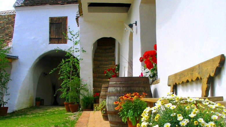 Traditioneller Innenhof mit Blumen und Holzfässern.