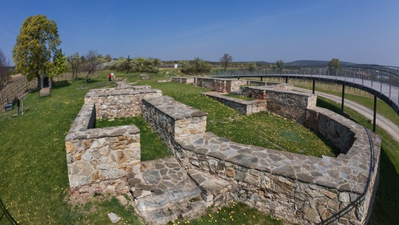 Ausgrabungsstätte mit Steinmauern und Aussichtssteg im Freien.