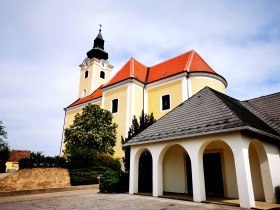 Pfarrkirche St. Nikolaus in R&ouml;schitz mit gelber Fassade und rotem Dach.