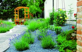 Ein gepflegter Garten mit Lavendel, einem Holzpavillon und gepflasterten Wegen.