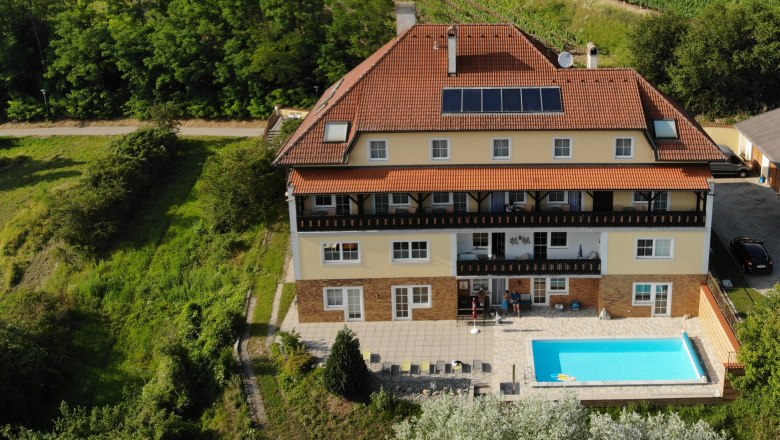 Pension Rudi, © Pension Rudi Luftaufnahme eines großen Hauses mit Pool und Solarpanelen, umgeben von Weinbergen.