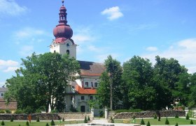 Barockkirche mit rotem Turm und Barockgarten im Vordergrund.